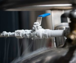 Liquid nitrogen frozen faucet and lever. Visible floating white condensation smoke from pressurized tank isolated close up shot Liquid nitrogen frozen faucet and lever. Visible floating white condensation smoke from pressurized tank isolated close up shot.