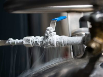 Liquid nitrogen frozen faucet and lever. Visible floating white condensation smoke from pressurized tank isolated close up shot Liquid nitrogen frozen faucet and lever. Visible floating white condensation smoke from pressurized tank isolated close up shot.